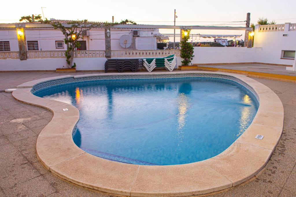 uma piscina com duas cadeiras e um edifício em Sa Paissa em Cala'n Porter