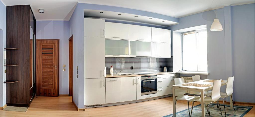 a kitchen with white cabinets and a table at Marszałkowska Apartment in Warsaw