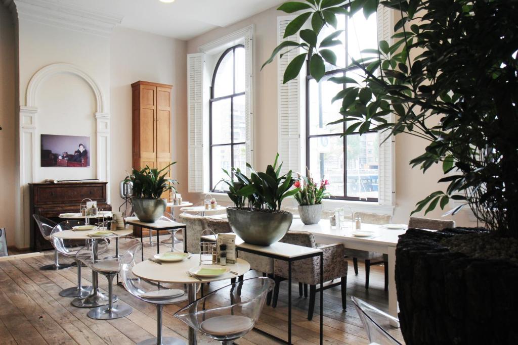 een restaurant met tafels en stoelen en potplanten bij Suitehotel Pincoffs in Rotterdam