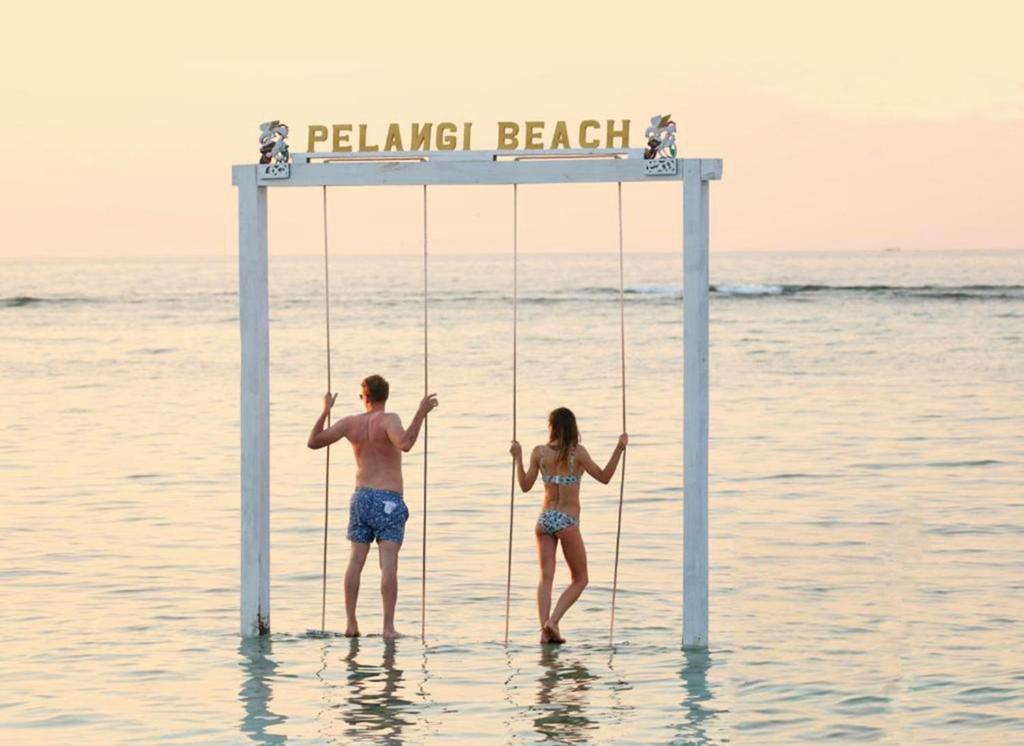 Pelangi Cottages Gili Air في غيلي آير: شخصان على مرجيحة في الماء