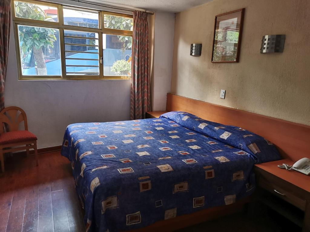 A double bedroom with a street-facing window, chair, and bedside telephone.