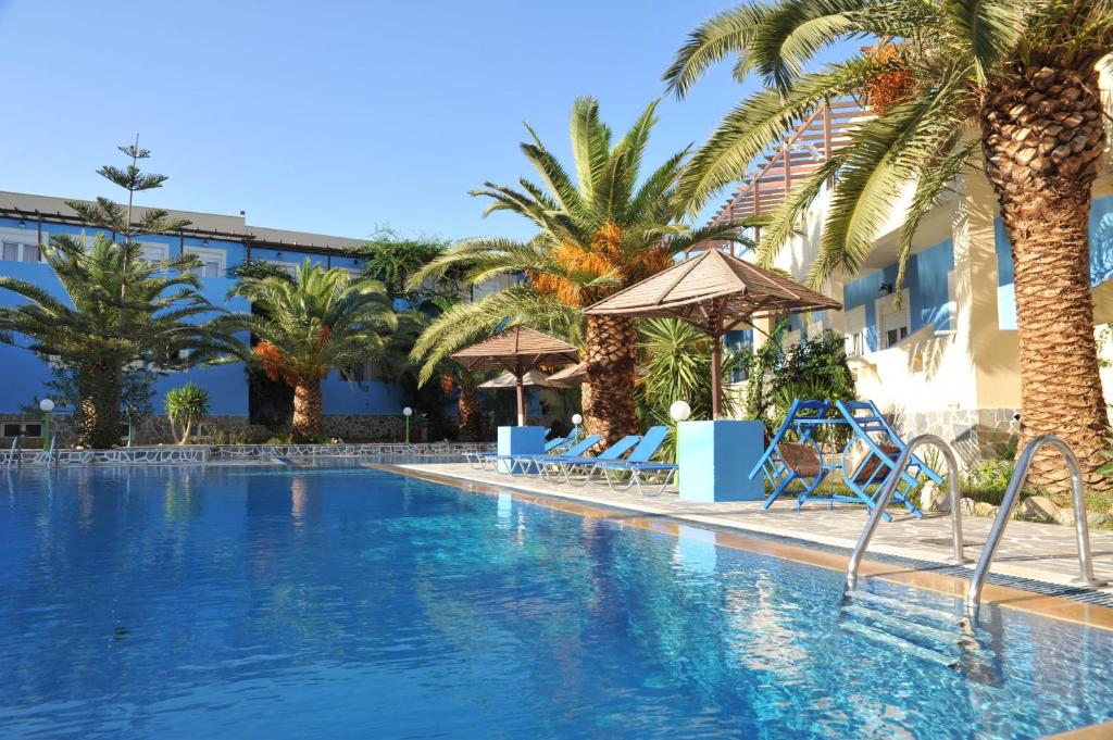 a large swimming pool with palm trees and a hotel at Efstathia Hotel in Xirokambos