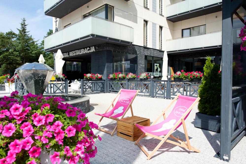 two pink chairs and flowers in front of a building at Cristal SPA in Dźwirzyno