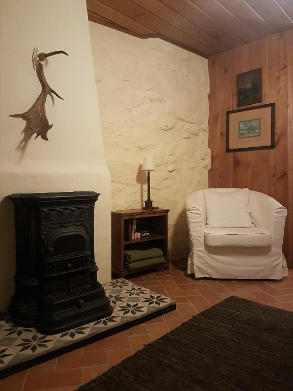 a living room with a fireplace and a white chair at Abrigo Montesinho in Montezinho