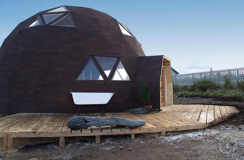 Domos by Toore Patagonia في بويرتو ناتالز: بيت مستدير مع نافذة كبيرة وسطح خشبي