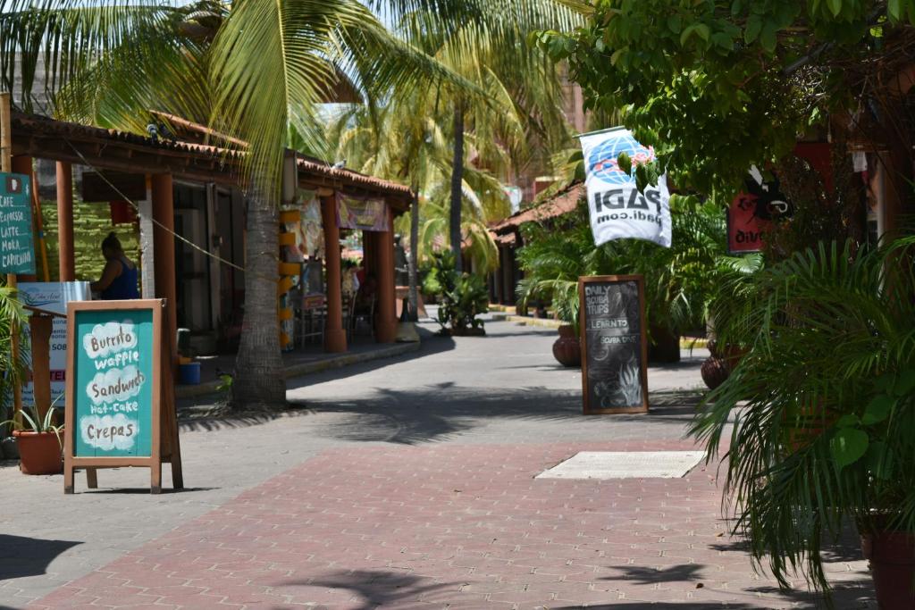 a street with palm trees and a sign on a sidewalk at Isabel Suites in Zihuatanejo
