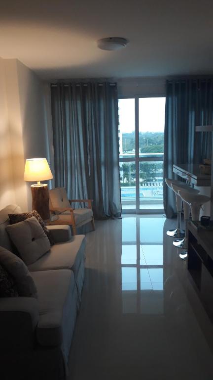 sala de estar con sofá, mesa y ventana en Ilha Pura Barra Temporada, en Río de Janeiro