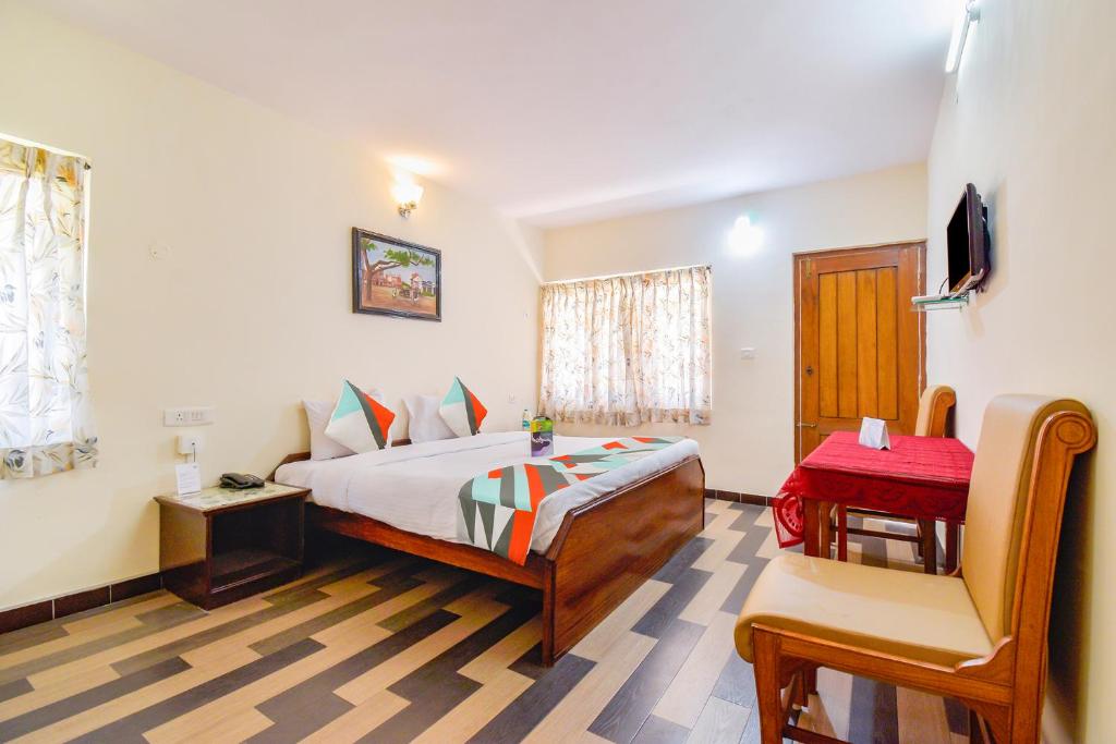 een slaapkamer met een bed, een tafel en een stoel bij FabExpress Wenlock Homes in Ooty