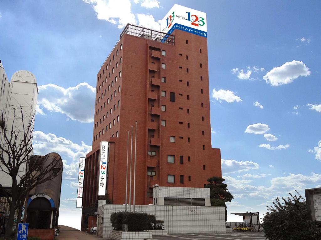 北九州的住宿－小倉1-2-3酒店，一座高大的红色建筑,上面有标志