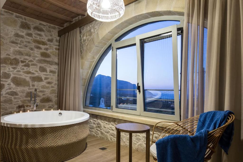 a bathroom with a tub and a large window at Kamartsos Villa 3 in Áyios Yeóryios