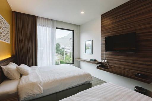 Habitación de hotel con 2 camas y ventana grande. en TOBEDzZ HOTEL en Ranong