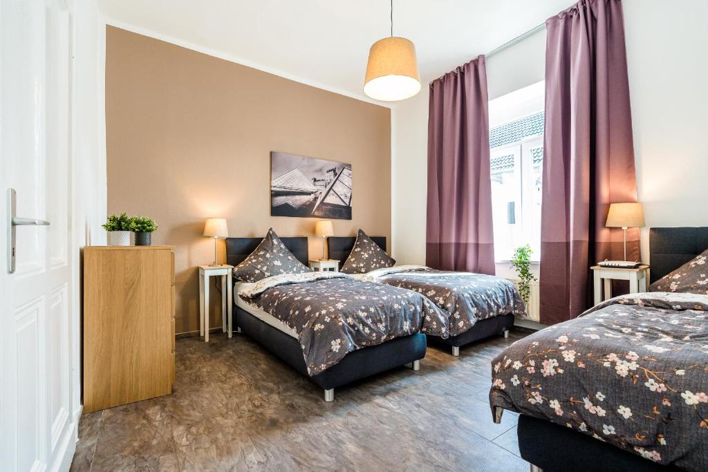 2 Betten in einem Zimmer mit lila Vorhängen in der Unterkunft Adora Apartment Hilden in Hilden