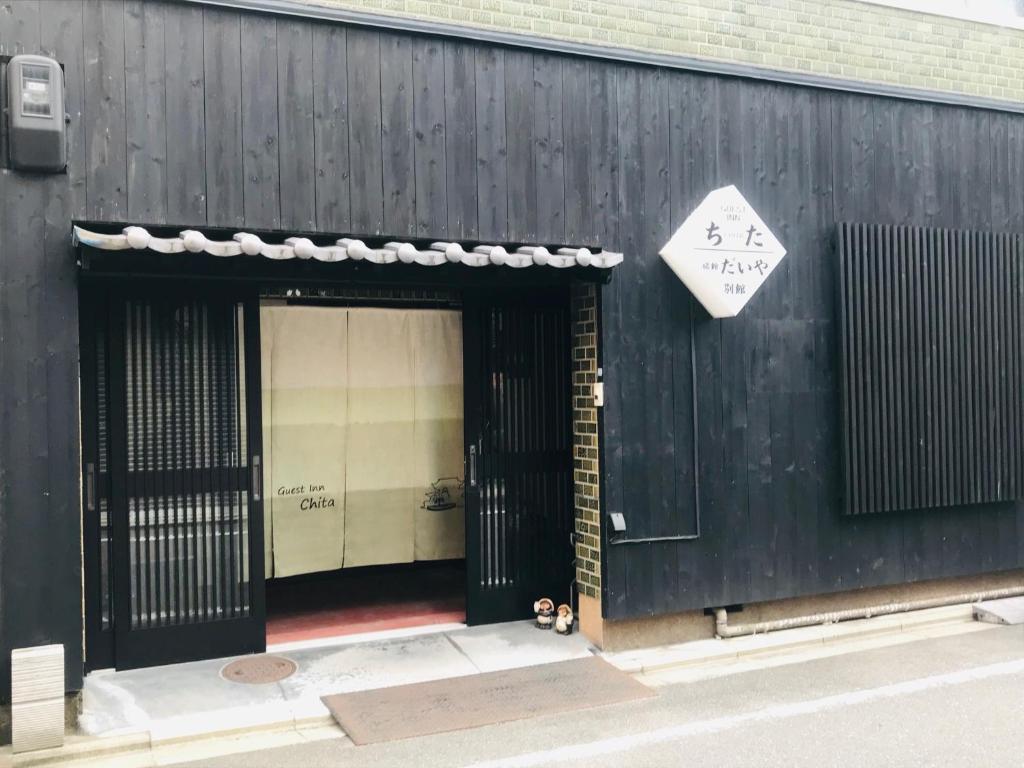 a black building with a door with a sign on it at Guest Inn Chita in Kyoto