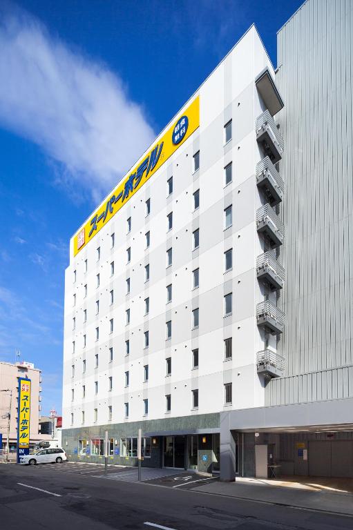 a large white building with a yellow sign on it at Super Hotel Hakodate in Hakodate