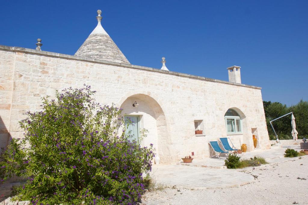 a stone building with two blue chairs in front of it at L'Uliveto in Cisternino