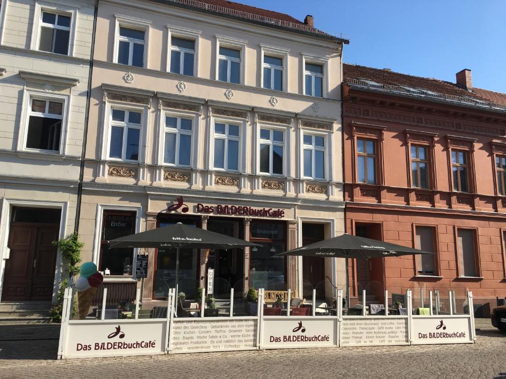 un restaurante con sombrillas frente a un edificio en Bilderbuchcafe - Pension Markt 7 en Havelberg
