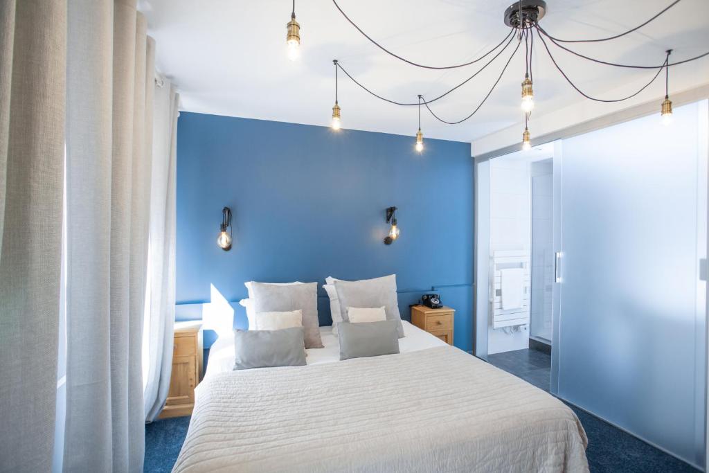 a blue bedroom with a large bed with white sheets at Hôtel Le Rapp in Colmar