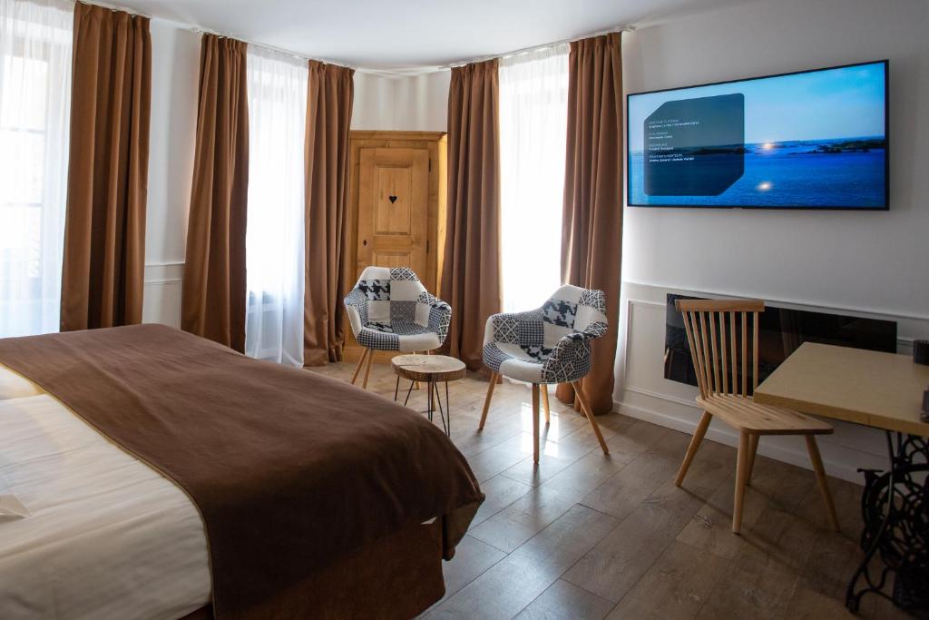 a hotel room with a bed and chairs and a desk at Hôtel Le Rapp in Colmar