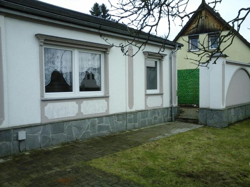 ein weißes Haus mit zwei Fenstern und einem Hof in der Unterkunft Ferienhaus Günther Werder-Havel in Werder