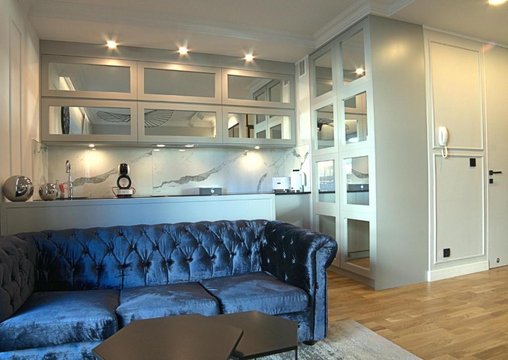 un salon avec un canapé bleu et une table dans l'établissement Blue Velvet Premium Apartments, à Toruń