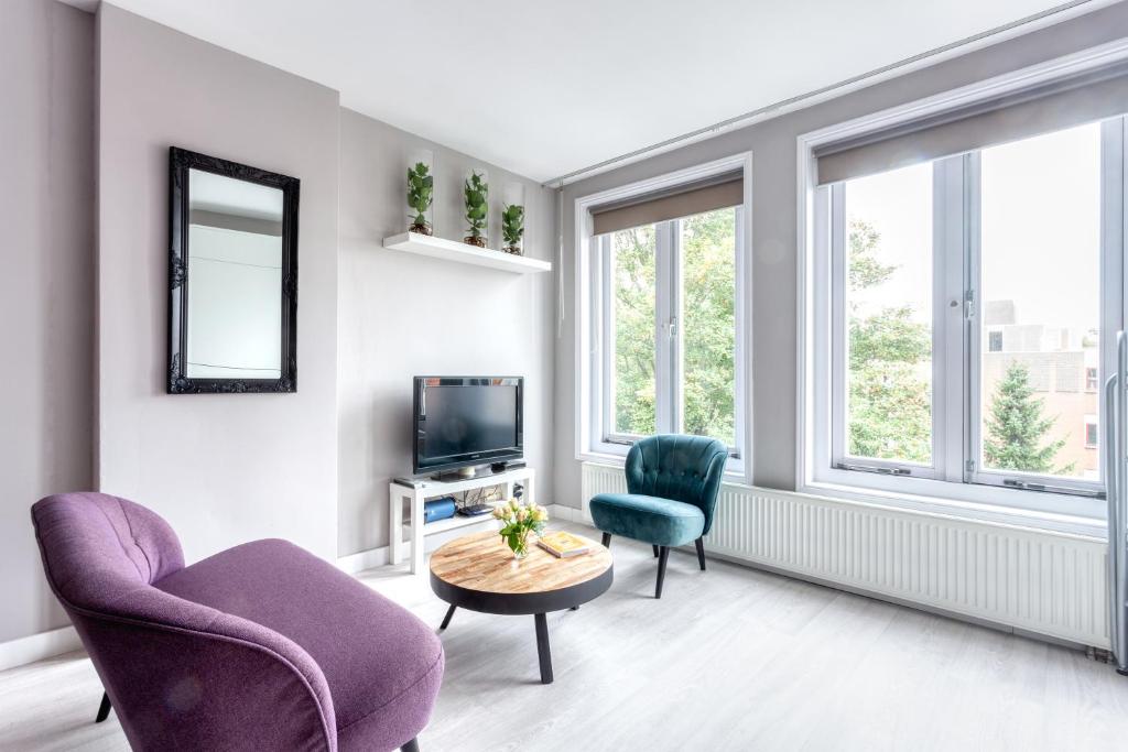 a living room with two chairs and a tv at Bed and Breakfast The Rose in Haarlem