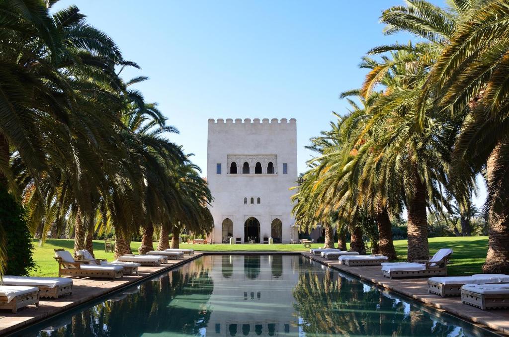 a large pool of water with palm trees at Ksar Char-Bagh Small Luxury Hotels in Marrakesh