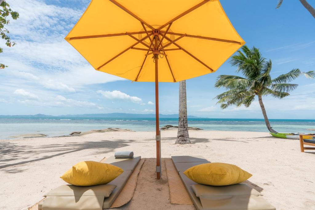 a yellow umbrella on a beach with two pillows at Princess Paradise Koh Phangan in Haad Rin