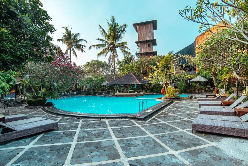 een zwembad in een resort met stoelen en een toren bij Jogja Village in Yogyakarta