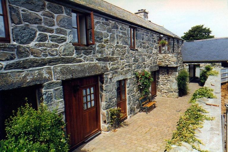 una casa de piedra con una puerta y un patio de ladrillo en Ystumgwern Luxury Barn Conversions, en Dyffryn