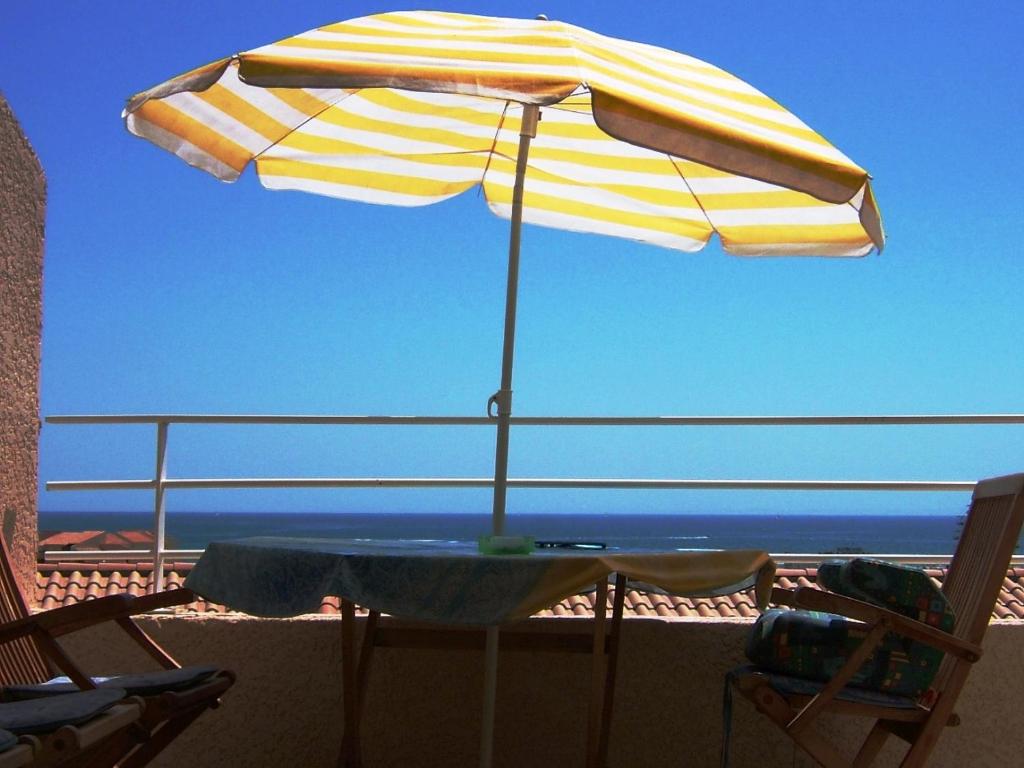 einen Tisch mit Sonnenschirm auf dem Balkon in der Unterkunft T3 vue mer et plage, avec wifi et parking in Saint Pierre La Mer