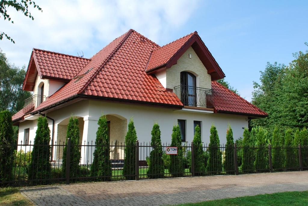 a house with a red roof and a fence at Willa w Rewalu in Rewal