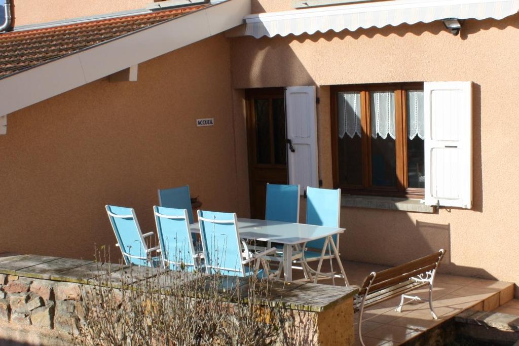 una mesa y sillas en un patio con mesa y sillón en Le Clos du Jubin, en Saint-Forgeux