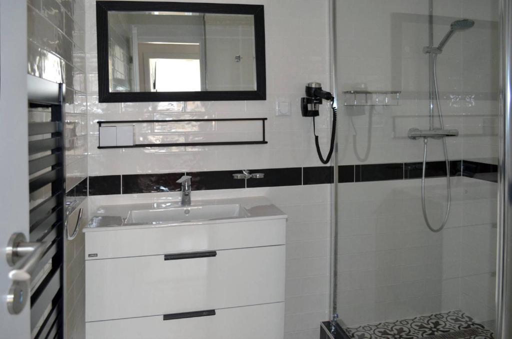 a white bathroom with a sink and a shower at Hotel Na Baste in Jablonec nad Nisou