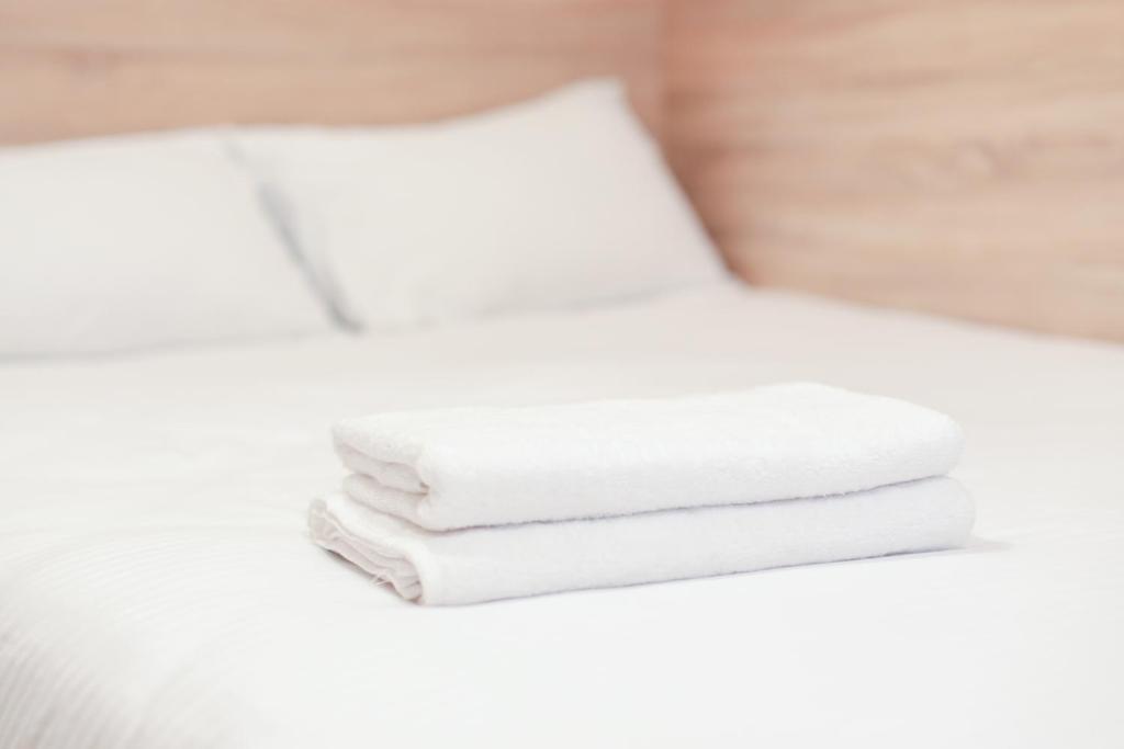 una pila de toallas blancas sentadas en una cama en Міні-Smart економ квартира в центрі для пари-3 хв до Оперного Театру en Leópolis