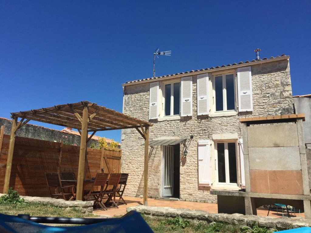 a stone house with a wooden pergola in front of it at Le Petit Nid Cosy in Esnandes