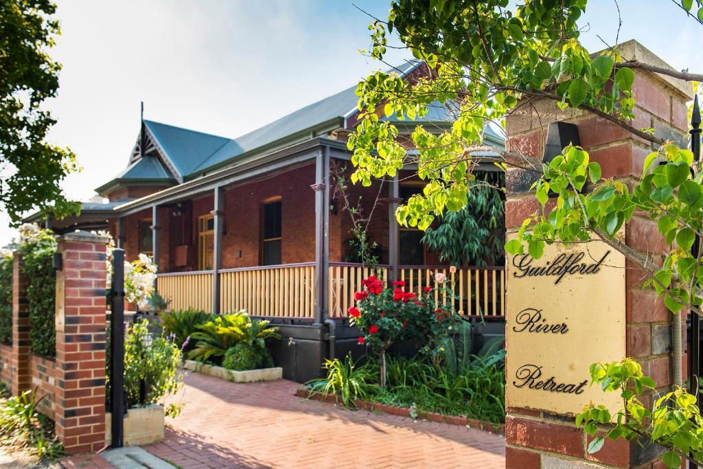 ein Backsteinhaus mit einem Zaun und Blumen in der Unterkunft Guildford River Retreat in Perth