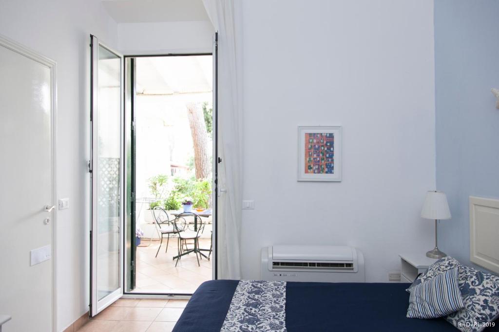 a bedroom with a bed and a patio with a table at Il Miraggio in Fregene