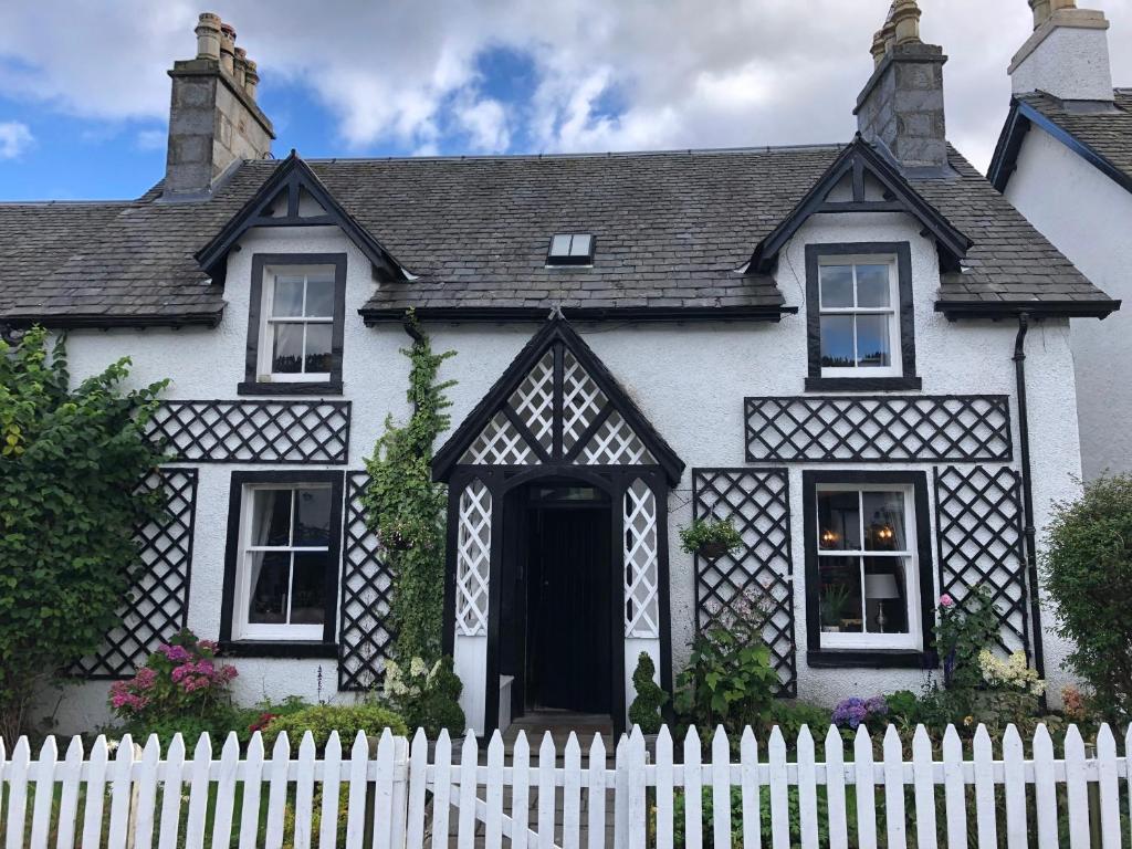 uma casa a preto e branco com uma cerca branca em Chefs cottage em Kenmore