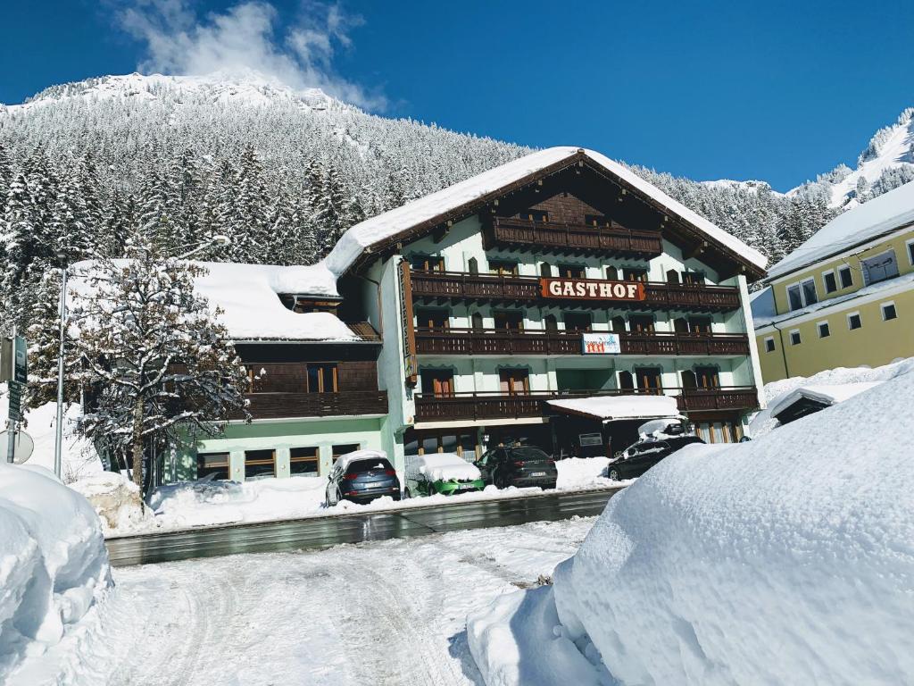 um edifício coberto de neve com carros estacionados em frente em T3 Gasthof Spullersee em Wald am Arlberg