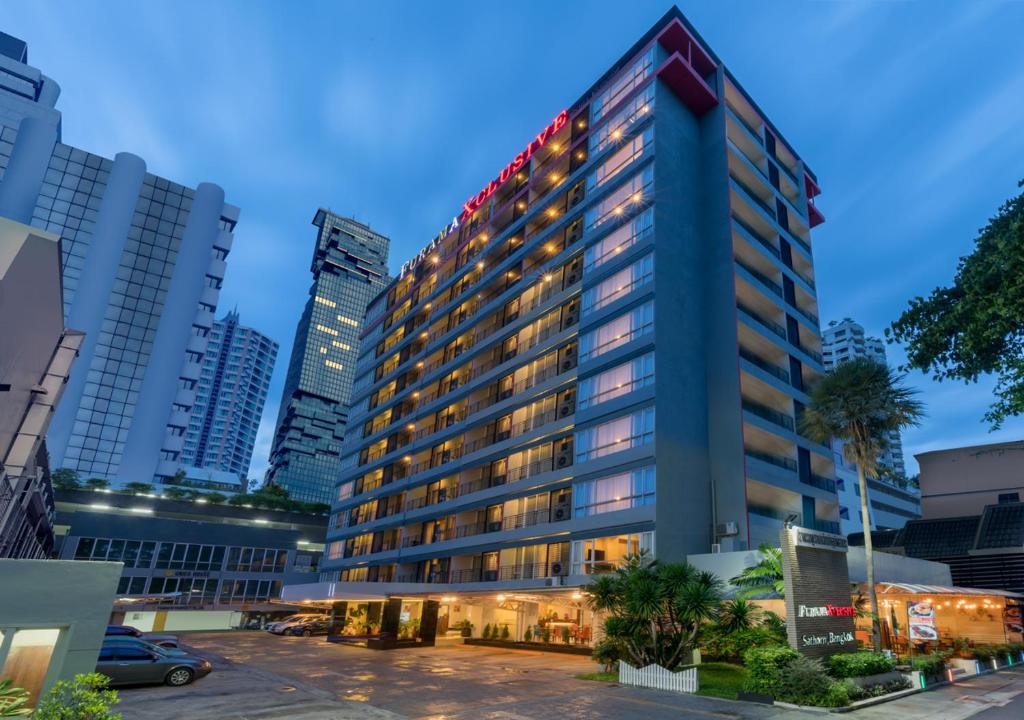 a tall building with lights on it in a city at FuramaXclusive Sathorn, Bangkok in Bangkok