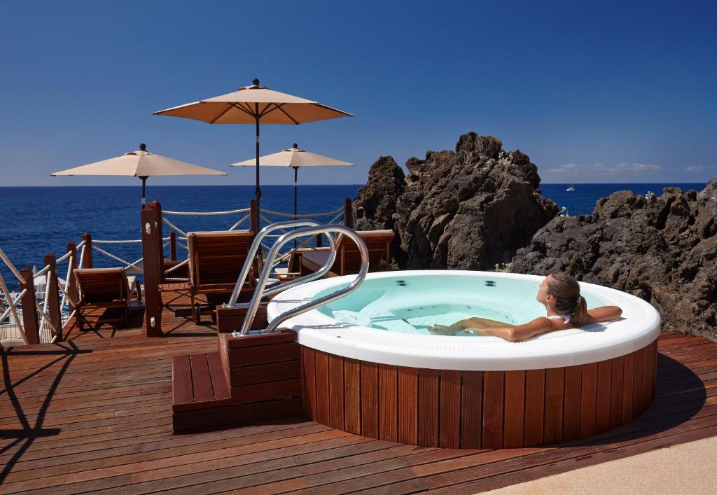 a woman sitting in a hot tub on a deck at The Cliff Bay - PortoBay in Funchal