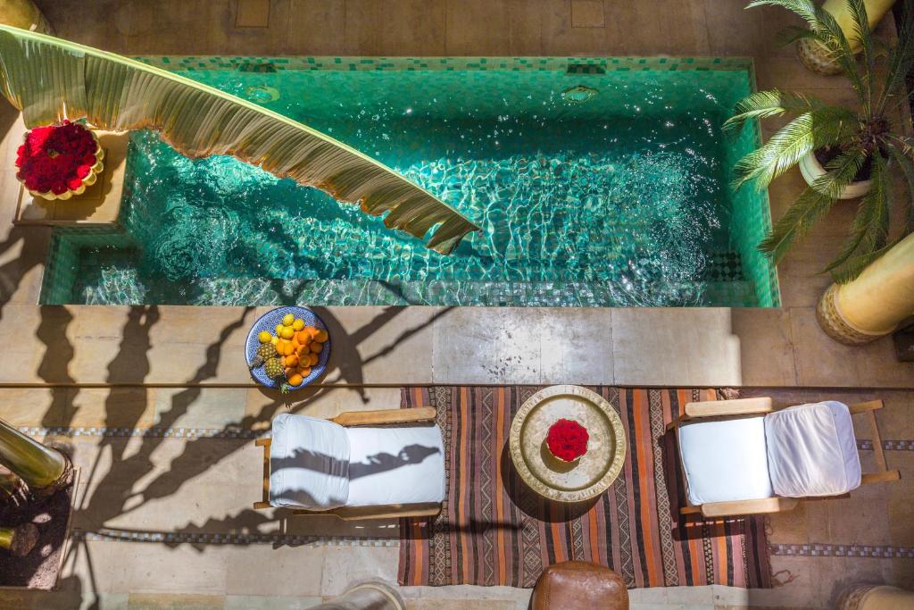 een uitzicht over een zwembad met een tafel en stoelen bij Riad Azoulay in Marrakesh