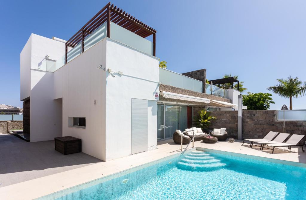 a villa with a swimming pool and a house at Luxury BKM in Playa del Duque in Adeje