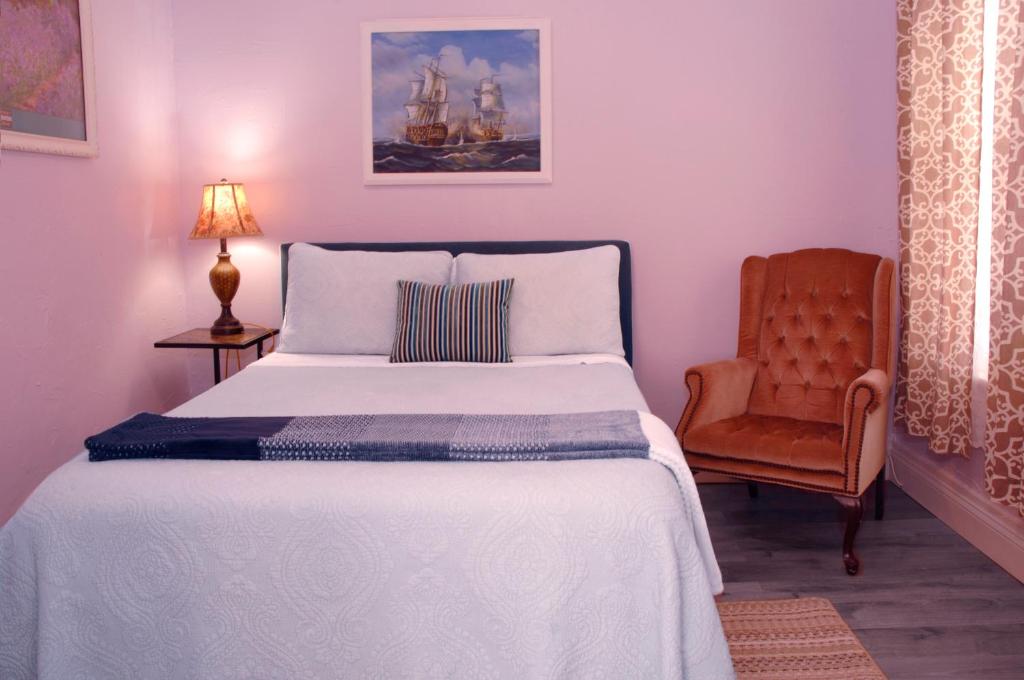 ein Schlafzimmer mit einem weißen Bett und einem Stuhl in der Unterkunft Adorable Historic Downtown Apartment in St. Augustine