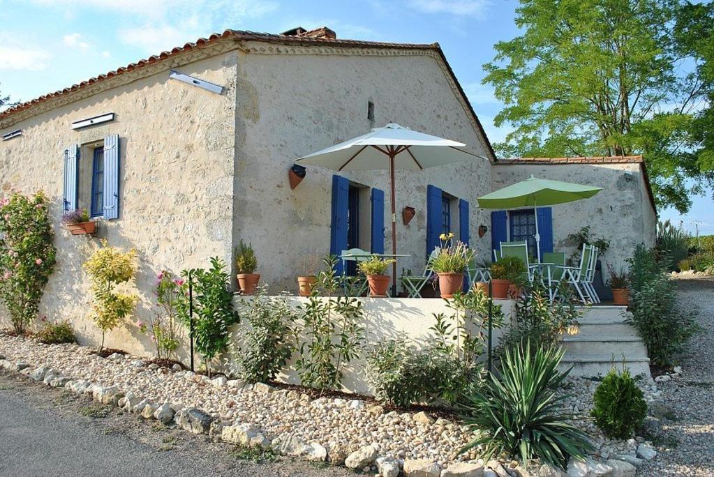 a house with an umbrella and a table and chairs at L'Aulerie in Saint-Méard-de-Gurçon