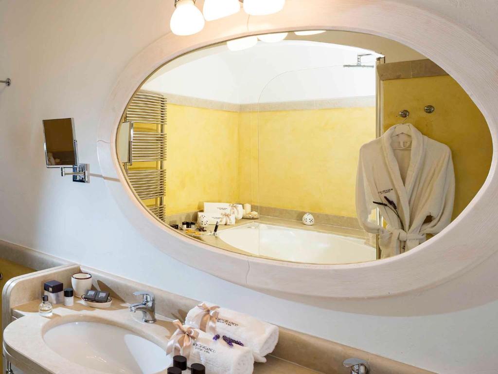 a bathroom with a tub and a sink and a mirror at Borgobianco Resort & Spa Polignano - MGallery Collection in Polignano a Mare