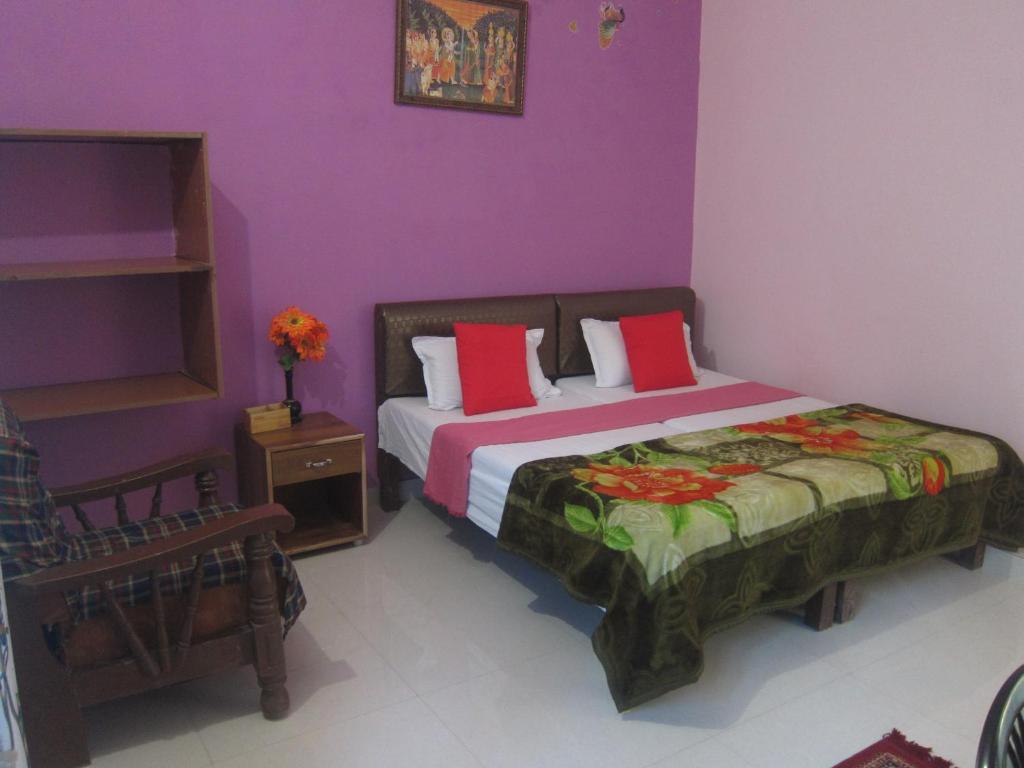 Un dormitorio con una cama con almohadas rojas y paredes moradas. en Kedar Guest House -Feel At Home, en Varanasi