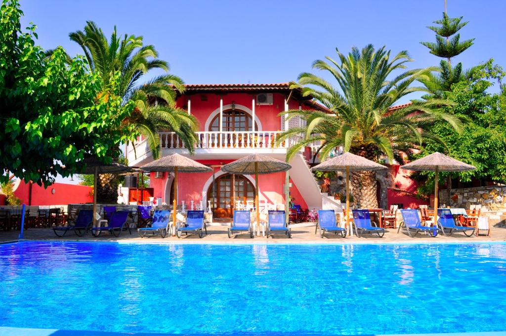um resort com uma grande piscina com cadeiras e guarda-sóis em Ilios Studios em Pefki