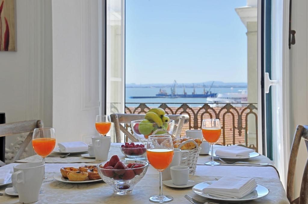 een tafel met eet- en wijnglazen en uitzicht op de oceaan bij Localtraveling ALFAMA River View - Family Apartments in Lissabon