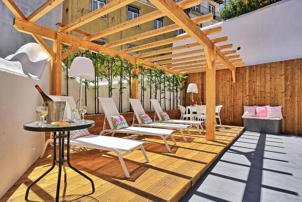 a patio with white chairs and tables and wooden walls at Localtraveling Cathedral & Castle - Family Apartments in Lisbon